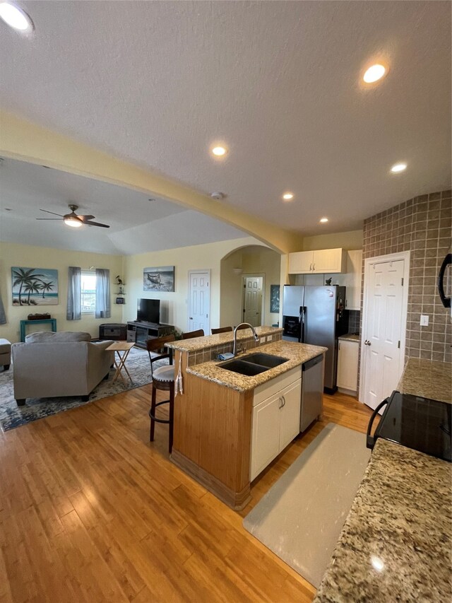 kitchen with white cabinetry, sink, appliances with stainless steel finishes, and a center island with sink