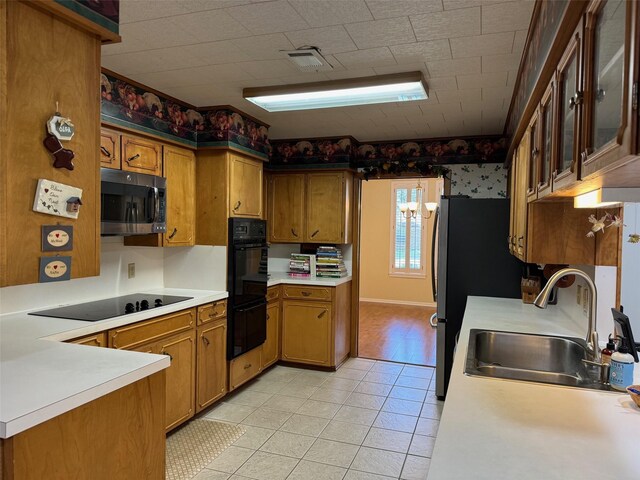 713 Sarah Jo St, La Grange, TX 78945 - kitchen featuring black appliances, brown cabinets, a sink, light countertops, and light tile patterned flooring