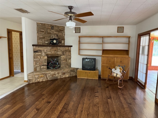 unfurnished living room featuring a stone fireplace, hardwood / wood-style flooring, and ceiling fan