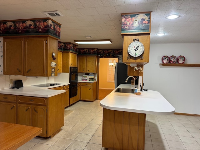 kitchen with light tile patterned floors, black appliances, sink, and kitchen peninsula