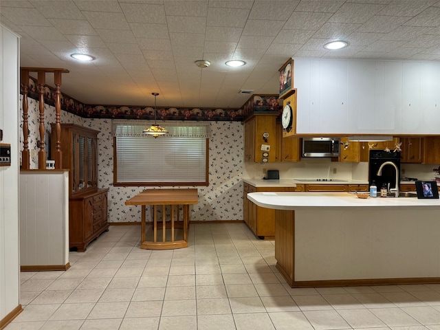 kitchen featuring decorative light fixtures, black appliances, light tile patterned floors, sink, and kitchen peninsula