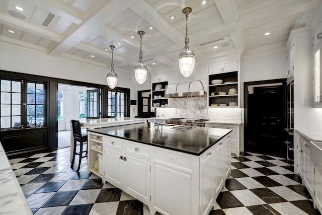 kitchen featuring backsplash, white cabinets, light tile floors, and a center island