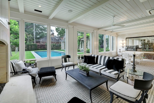 sunroom with ceiling fan and beamed ceiling