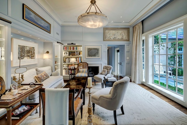 living room featuring built in features, light hardwood / wood-style flooring, and crown molding