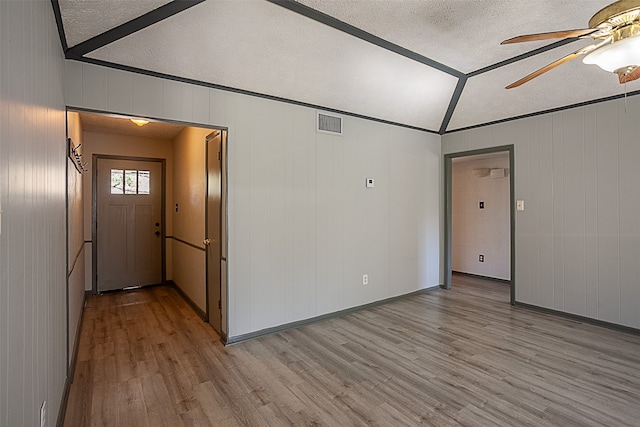 empty room with lofted ceiling, a textured ceiling, ceiling fan, and light wood-type flooring