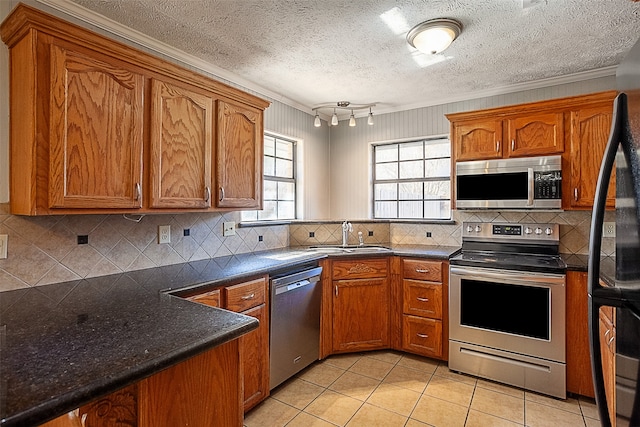 kitchen with appliances with stainless steel finishes, light tile flooring, backsplash, a textured ceiling, and sink