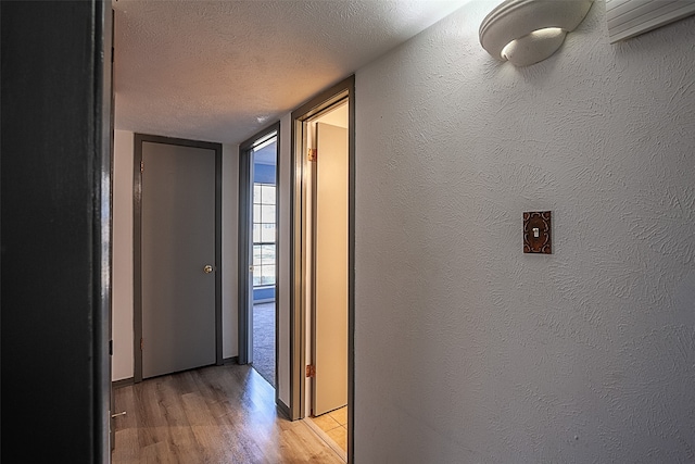 corridor featuring light hardwood / wood-style flooring and a textured ceiling