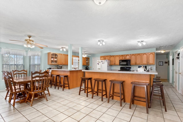 kitchen featuring black appliances, a kitchen breakfast bar, kitchen peninsula, and a textured ceiling