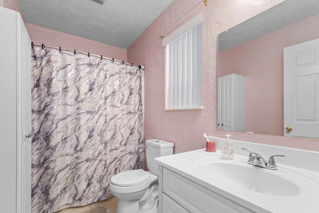 bathroom with vanity, a textured ceiling, and toilet