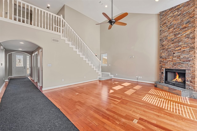 unfurnished living room featuring ceiling fan, wood-type flooring, and a stone fireplace