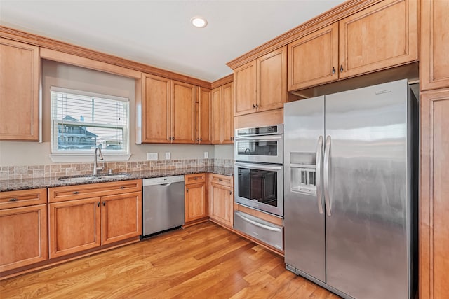 kitchen featuring light stone counters, sink, light hardwood / wood-style flooring, and appliances with stainless steel finishes