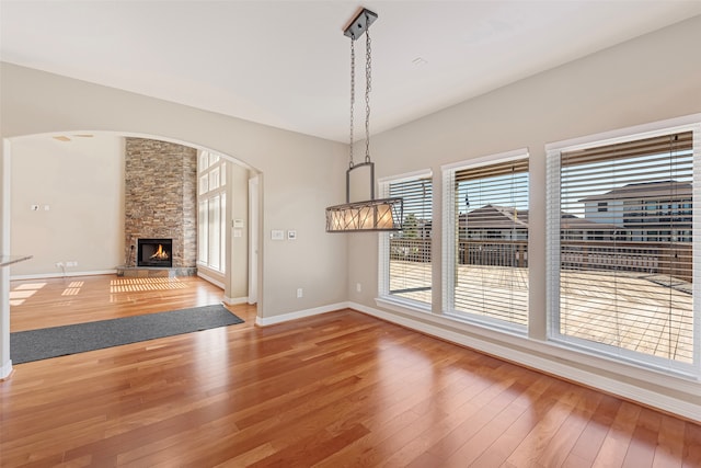 unfurnished dining area with wood-type flooring and a fireplace