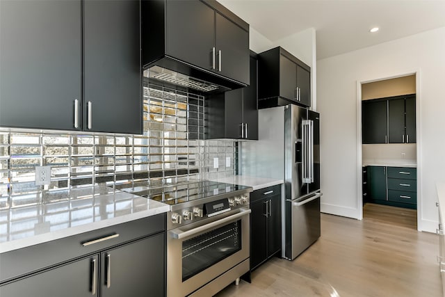 kitchen with light stone countertops, premium appliances, tasteful backsplash, and light hardwood / wood-style flooring