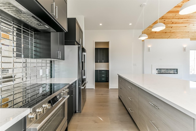 kitchen featuring exhaust hood, hanging light fixtures, light hardwood / wood-style flooring, decorative backsplash, and stainless steel range