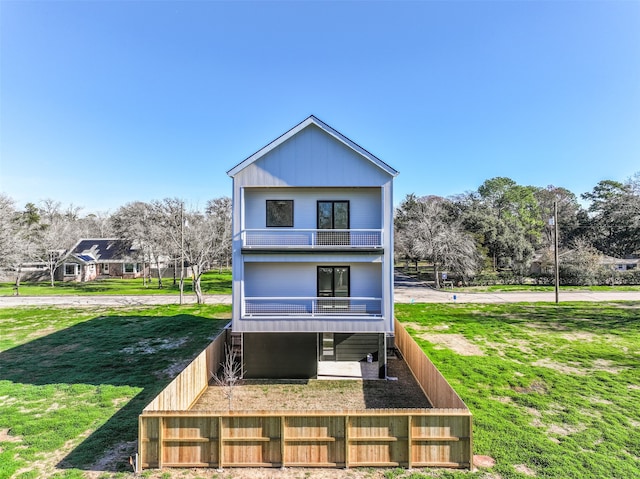 rear view of property featuring a balcony and a lawn