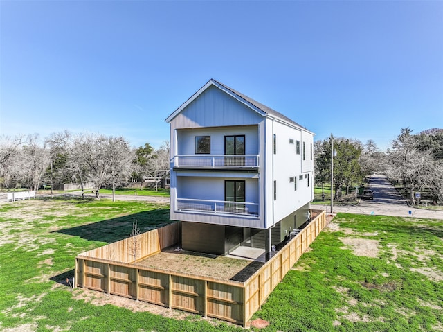 rear view of house with a balcony and a lawn