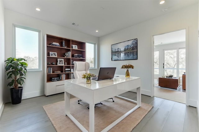 office with a healthy amount of sunlight and light hardwood / wood-style floors