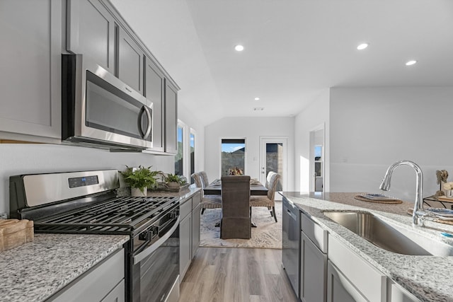 kitchen with appliances with stainless steel finishes, gray cabinets, light stone counters, and sink