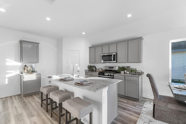 kitchen featuring sink, stainless steel appliances, gray cabinetry, and an island with sink