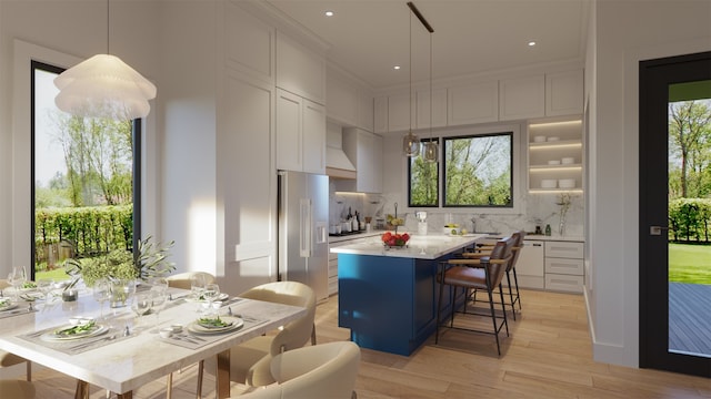 kitchen with a kitchen island, tasteful backsplash, light wood-type flooring, high quality fridge, and a kitchen breakfast bar