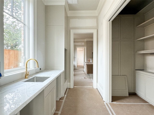 kitchen with ornamental molding, sink, white cabinets, and light stone counters