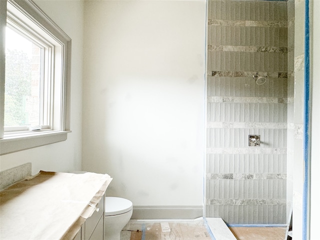 bathroom with vanity, toilet, and tiled shower