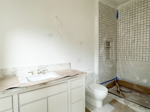 bathroom featuring vanity, toilet, tiled shower, and tile patterned flooring