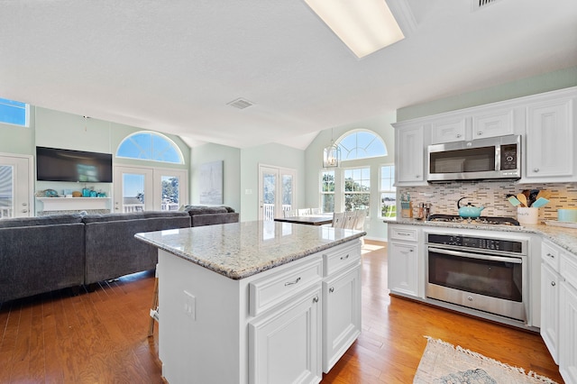 kitchen featuring appliances with stainless steel finishes, a kitchen island, light hardwood / wood-style floors, and white cabinetry