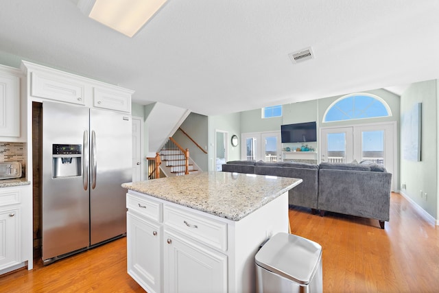 kitchen with white cabinets, stainless steel fridge with ice dispenser, light hardwood / wood-style flooring, and a center island