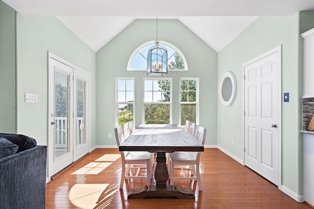 dining area with an inviting chandelier, lofted ceiling, and light wood-type flooring