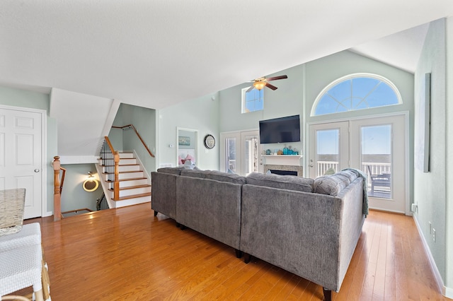 living room featuring ceiling fan, light hardwood / wood-style flooring, and a towering ceiling