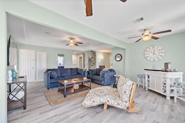 living room featuring a raised ceiling, light hardwood / wood-style floors, and ceiling fan