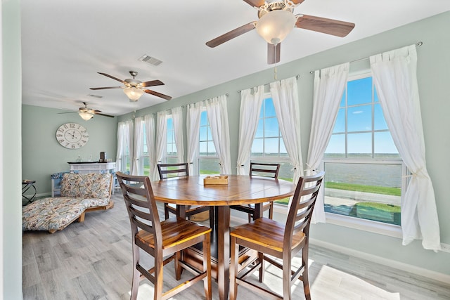 dining space featuring a water view, light hardwood / wood-style floors, and ceiling fan