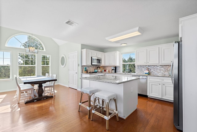 kitchen featuring dark hardwood / wood-style flooring, white cabinets, a kitchen island, and appliances with stainless steel finishes