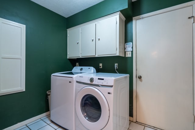 washroom featuring light tile flooring, a textured ceiling, cabinets, washer and clothes dryer, and hookup for an electric dryer