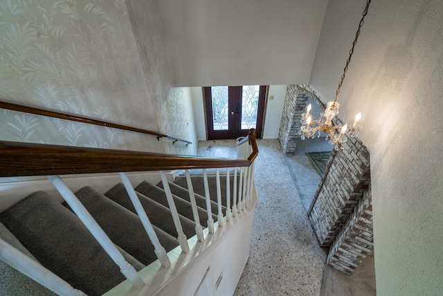 staircase with an inviting chandelier and french doors