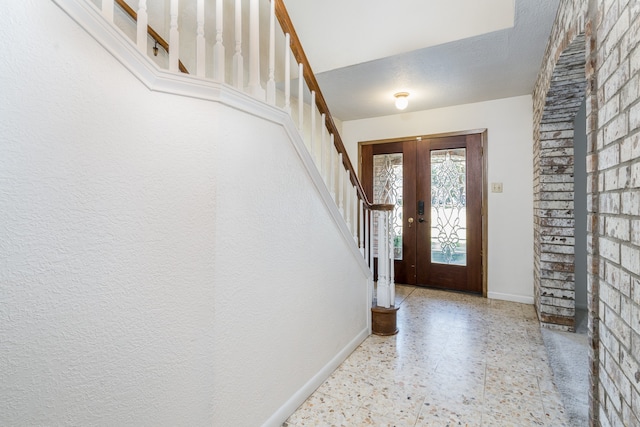 entrance foyer featuring a textured ceiling, light tile floors, and french doors