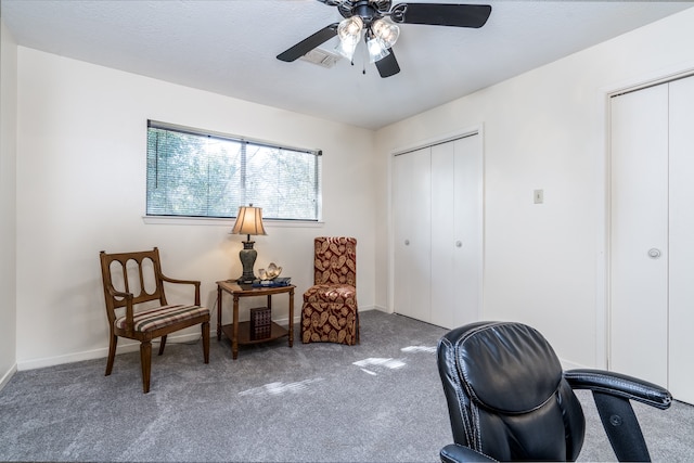 sitting room featuring dark carpet and ceiling fan