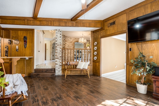 living room featuring decorative columns, a chandelier, dark hardwood / wood-style flooring, and beamed ceiling