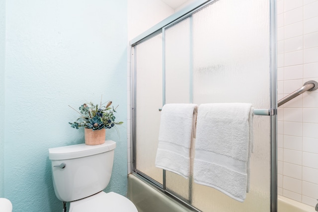 bathroom featuring enclosed tub / shower combo and toilet