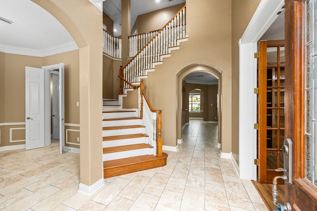 tiled foyer entrance featuring a high ceiling and crown molding