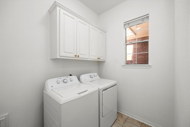 washroom with washing machine and clothes dryer, cabinets, and light tile floors