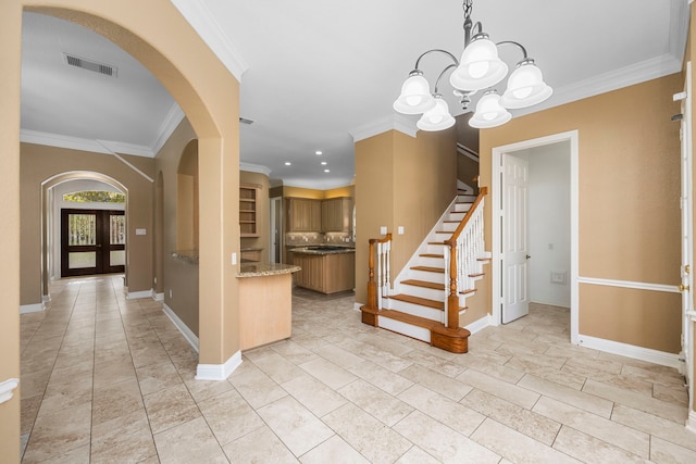 foyer with light tile flooring, ornamental molding, a notable chandelier, and french doors