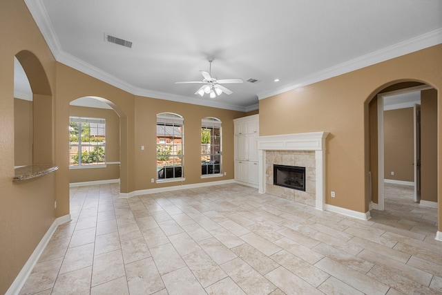 unfurnished living room with crown molding, light tile floors, ceiling fan, and a tile fireplace