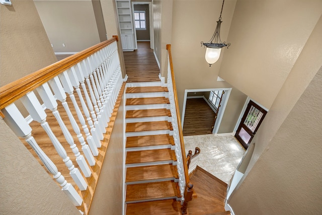 stairway with a high ceiling and wood-type flooring