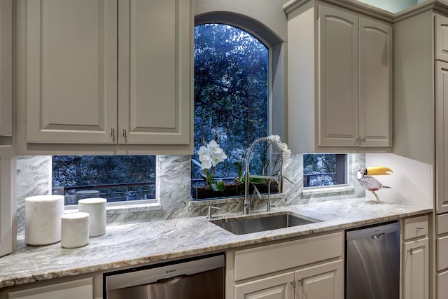 kitchen with tasteful backsplash, sink, light stone countertops, and dishwasher