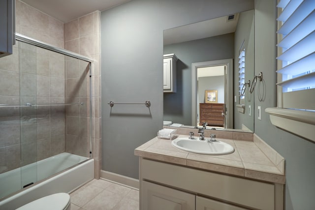 full bathroom featuring vanity with extensive cabinet space, tile floors, toilet, and combined bath / shower with glass door