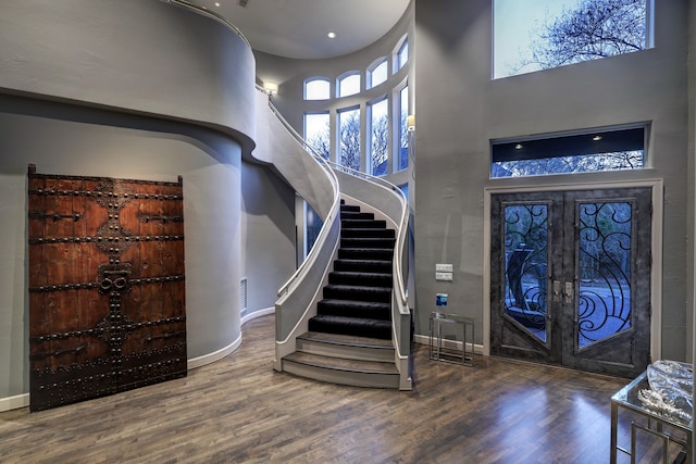 entryway with a towering ceiling, dark hardwood / wood-style floors, and french doors