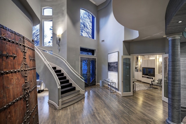 foyer entrance featuring dark hardwood / wood-style flooring, french doors, ornate columns, and a high ceiling