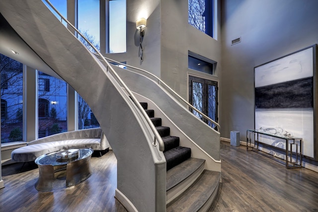 stairs with a towering ceiling, dark hardwood / wood-style floors, and french doors